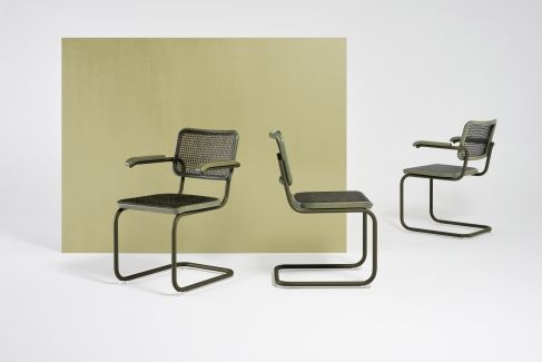 Drei grüne Thonet S 64 V Freischwinger Stühle mit Stahlrohrgestell und Armlehnen vor hellgrünem Hintergrund.