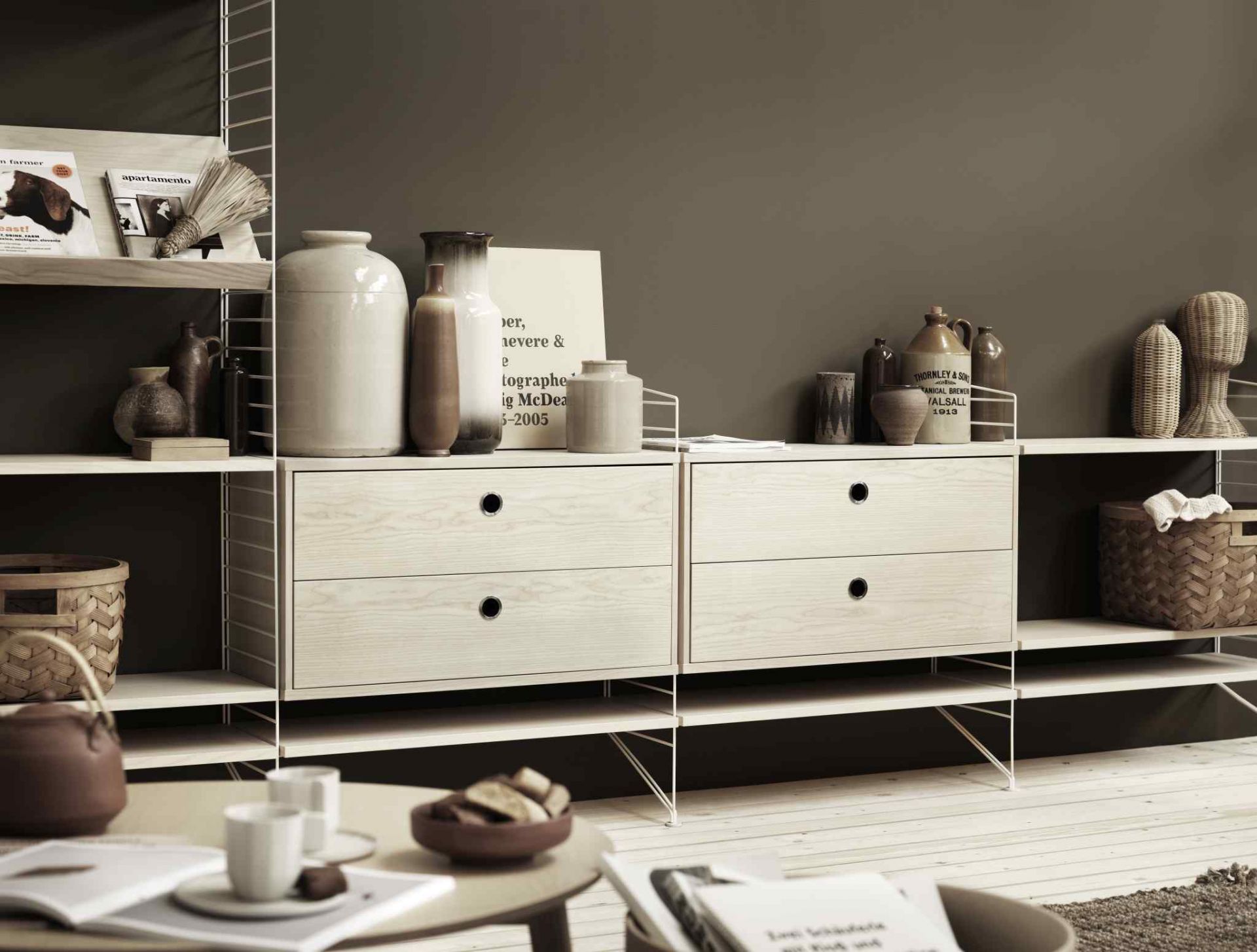 String Regalsystem mit Schubladen und Deko-Elementen. Bodenregal in Walnuss-Optik und schwarzem Metallrahmen. Modernes Wohnzimmerregal.