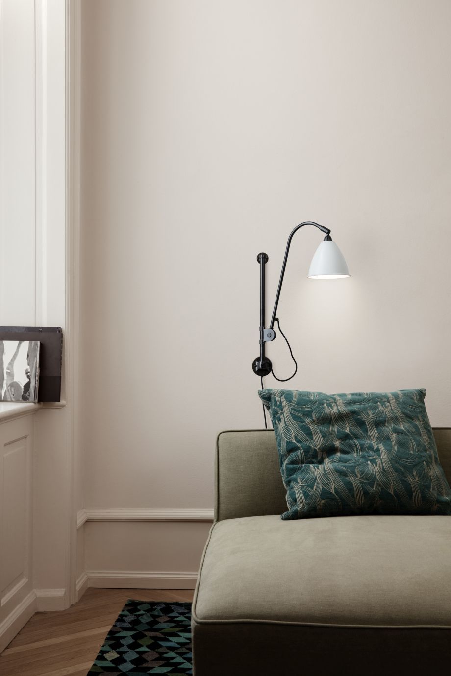 Bestlite Wandleuchte BL5 in Weiß/Messing von Gubi über Sofa, modernes skandinavisches Design.