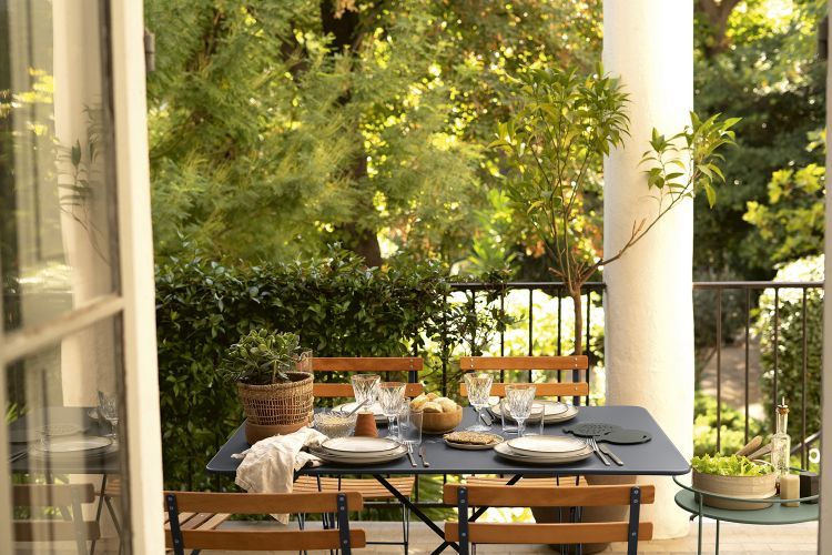 Fermob Bistro Tisch Outdoor auf einem Balkon mit Geschirr und Speisen für ein entspanntes Mittagessen.
