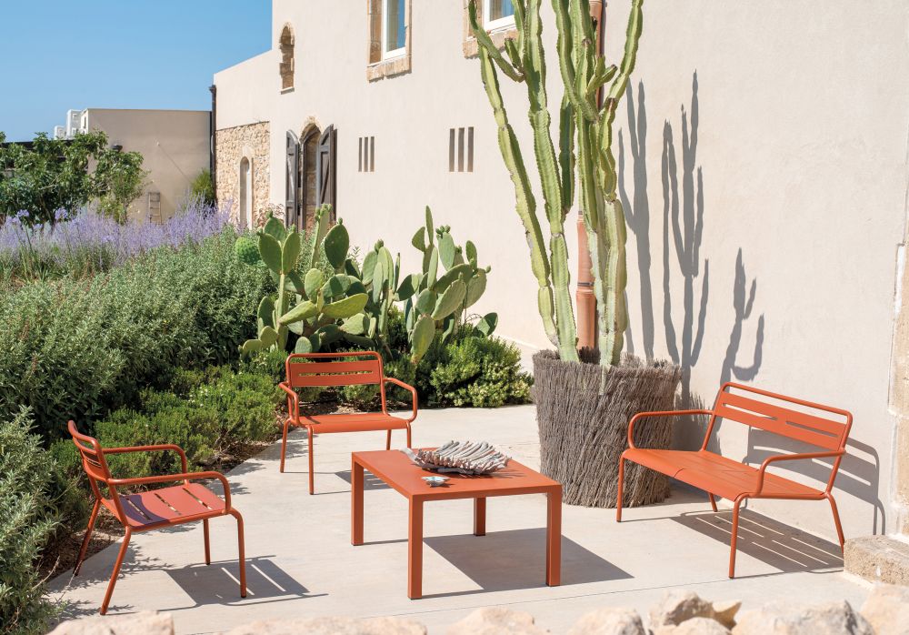 Orangefarbene Emu Star Lounge Gartenmöbel: Sessel, Bank und Tisch im mediterranen Garten.