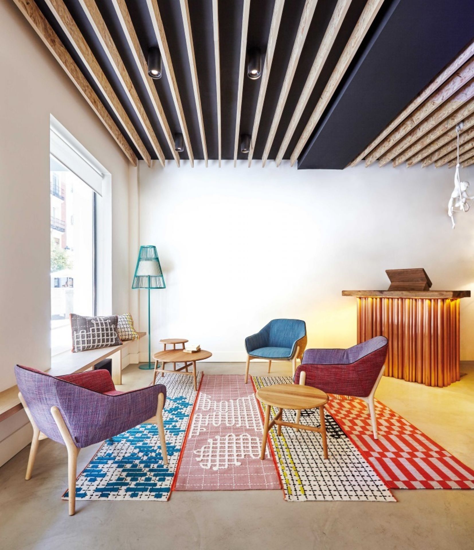 Wohnzimmer mit farbenfrohem Bandas Teppich von GAN, Sesseln und Holztischen. Handgefertigter Designer Teppich.