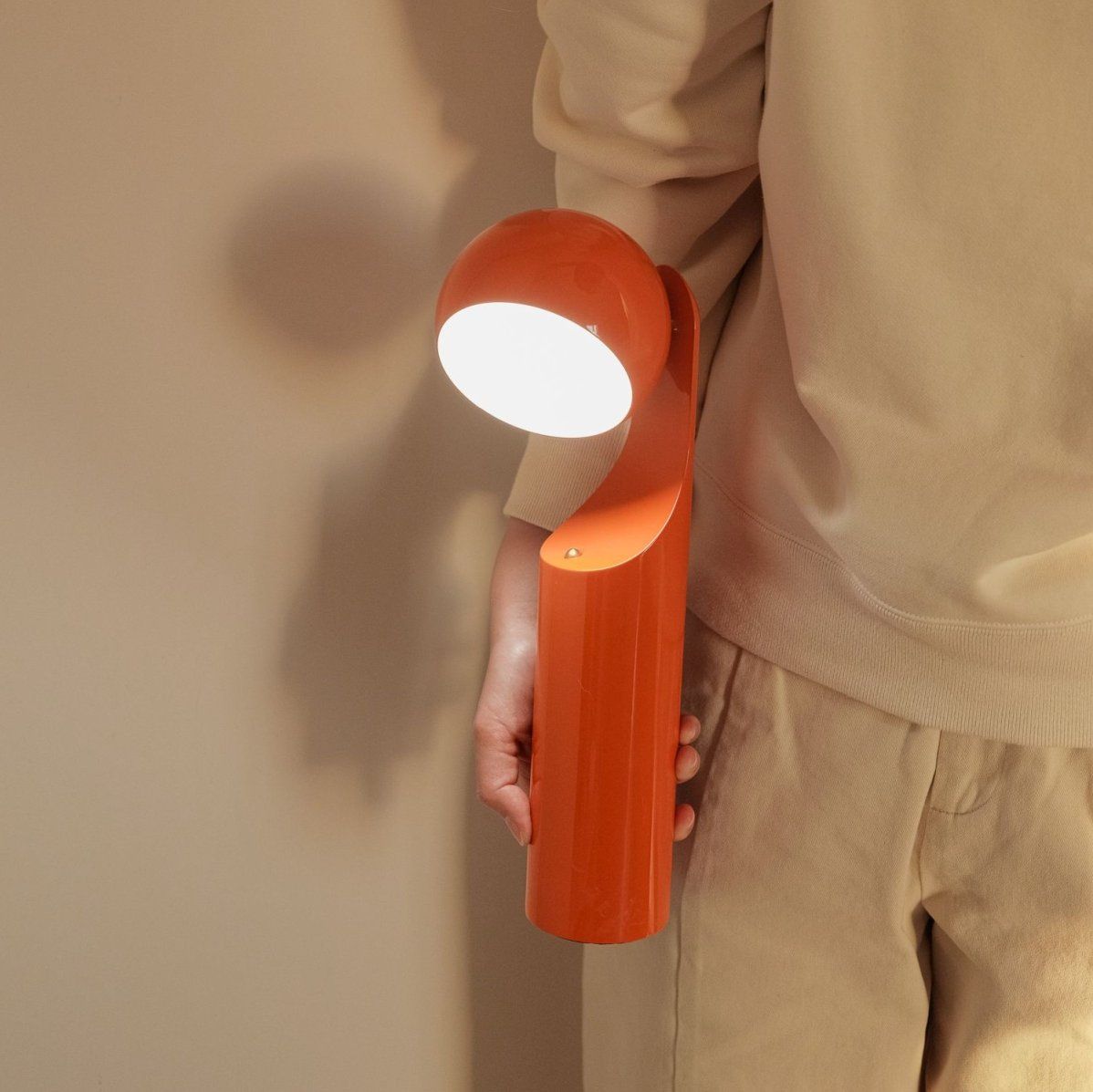 Person hält die orangefarbene Mono Akkuleuchte / Tischleuchte von house of home.