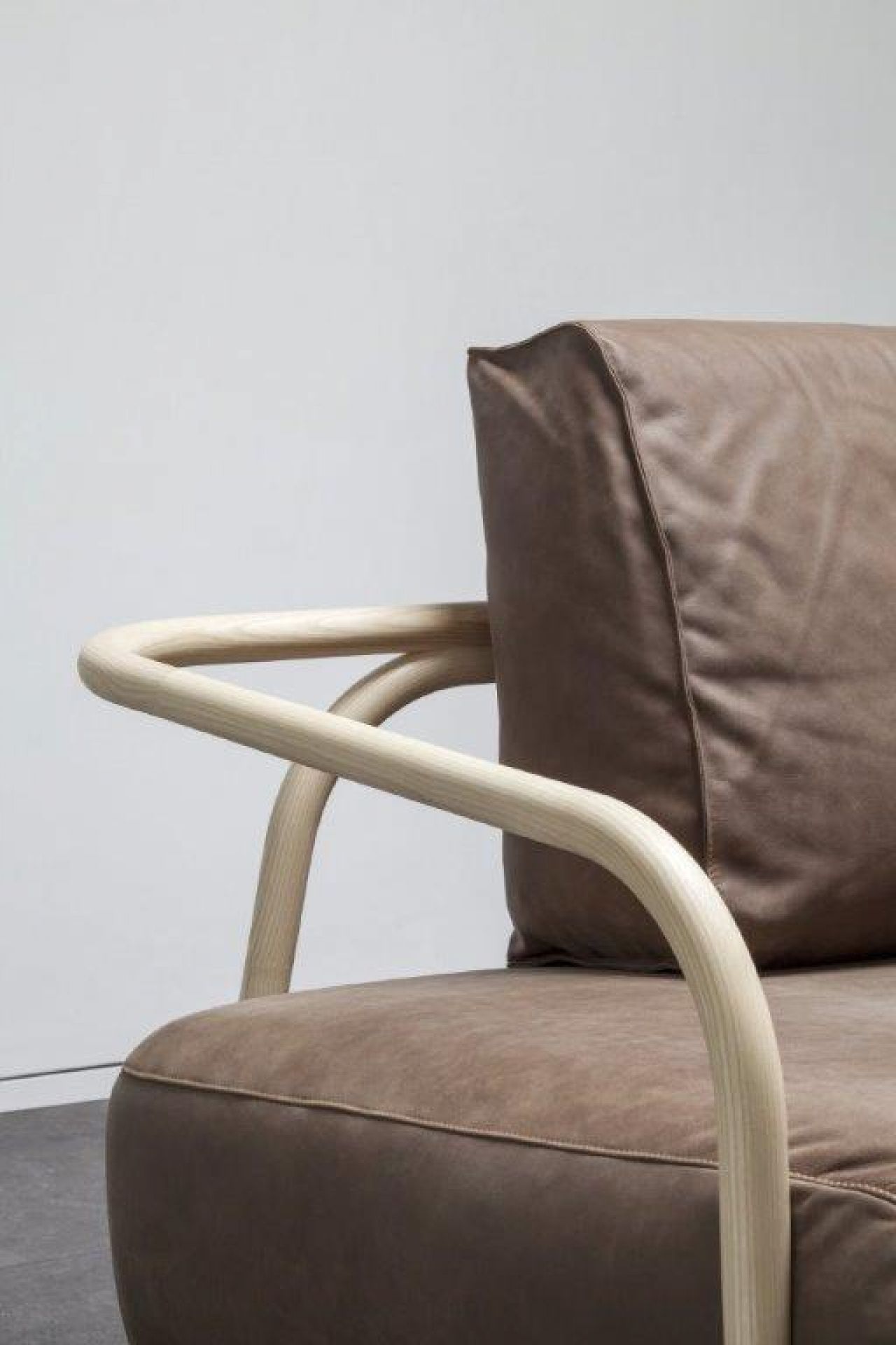 Detailaufnahme des 2002 Bugholz-Sofas von Thonet: Braunes Ledersofa mit hellen Holzarmlehnen, modernes Möbeldesign.