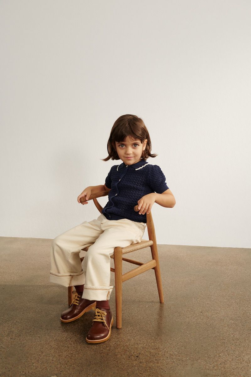 Mädchen sitzt auf CH24 Wishbone Stuhl von Carl Hansen & Søn. Kinderstuhl aus Holz.