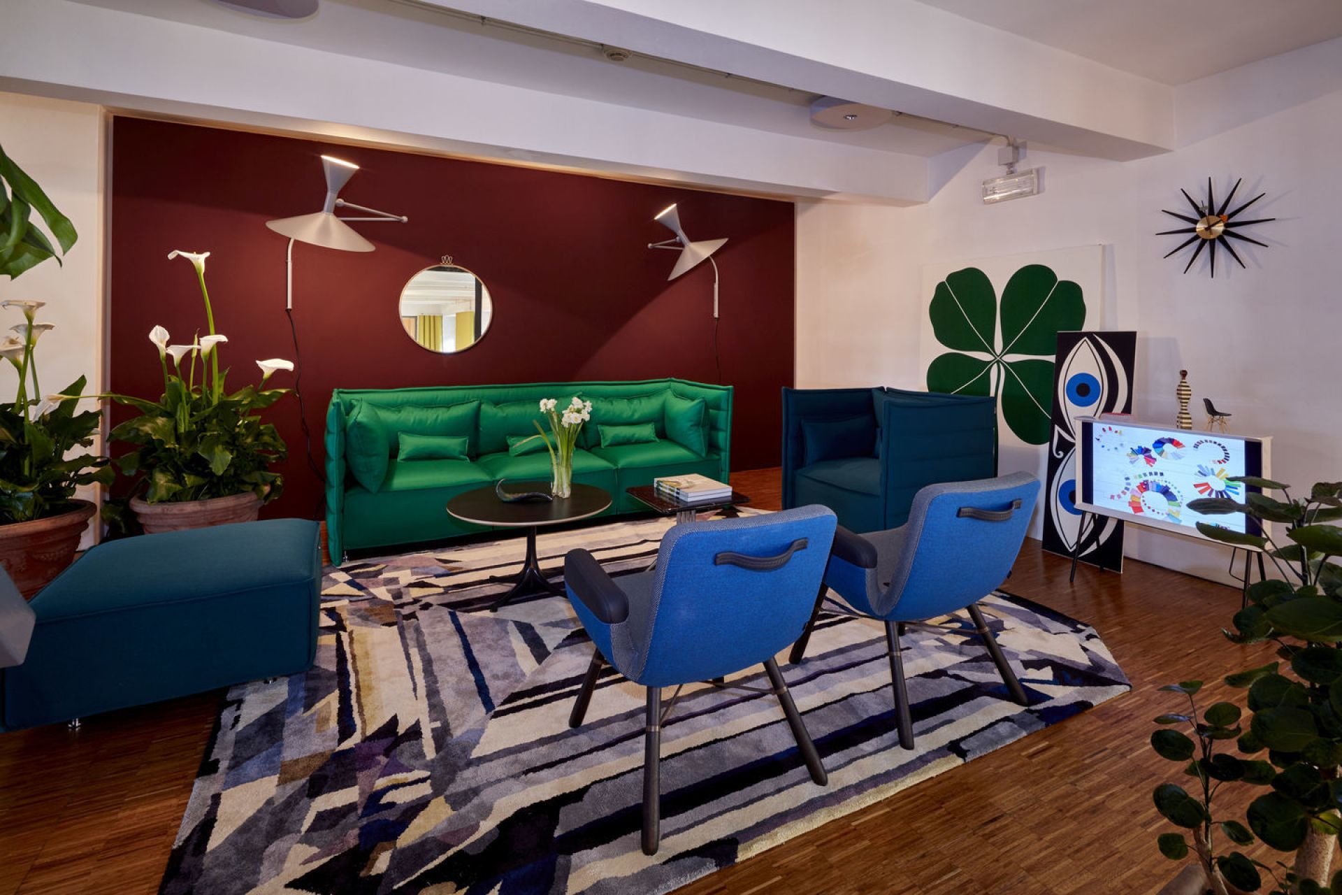 Wohnzimmer mit zwei blauen East River Sesseln von Vitra, Sofa, Teppich und Dekoration.