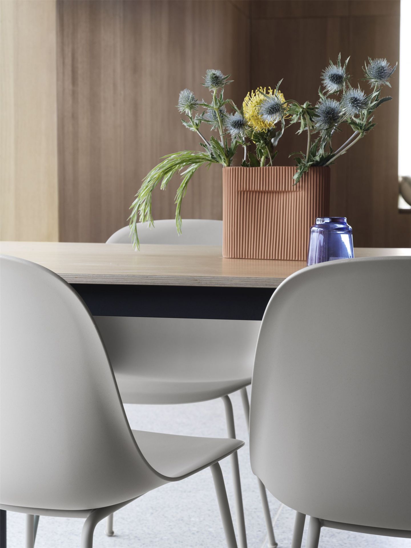 Nahaufnahme von zwei Fiber Side Chairs von Muuto in Grau an einem Esstisch.