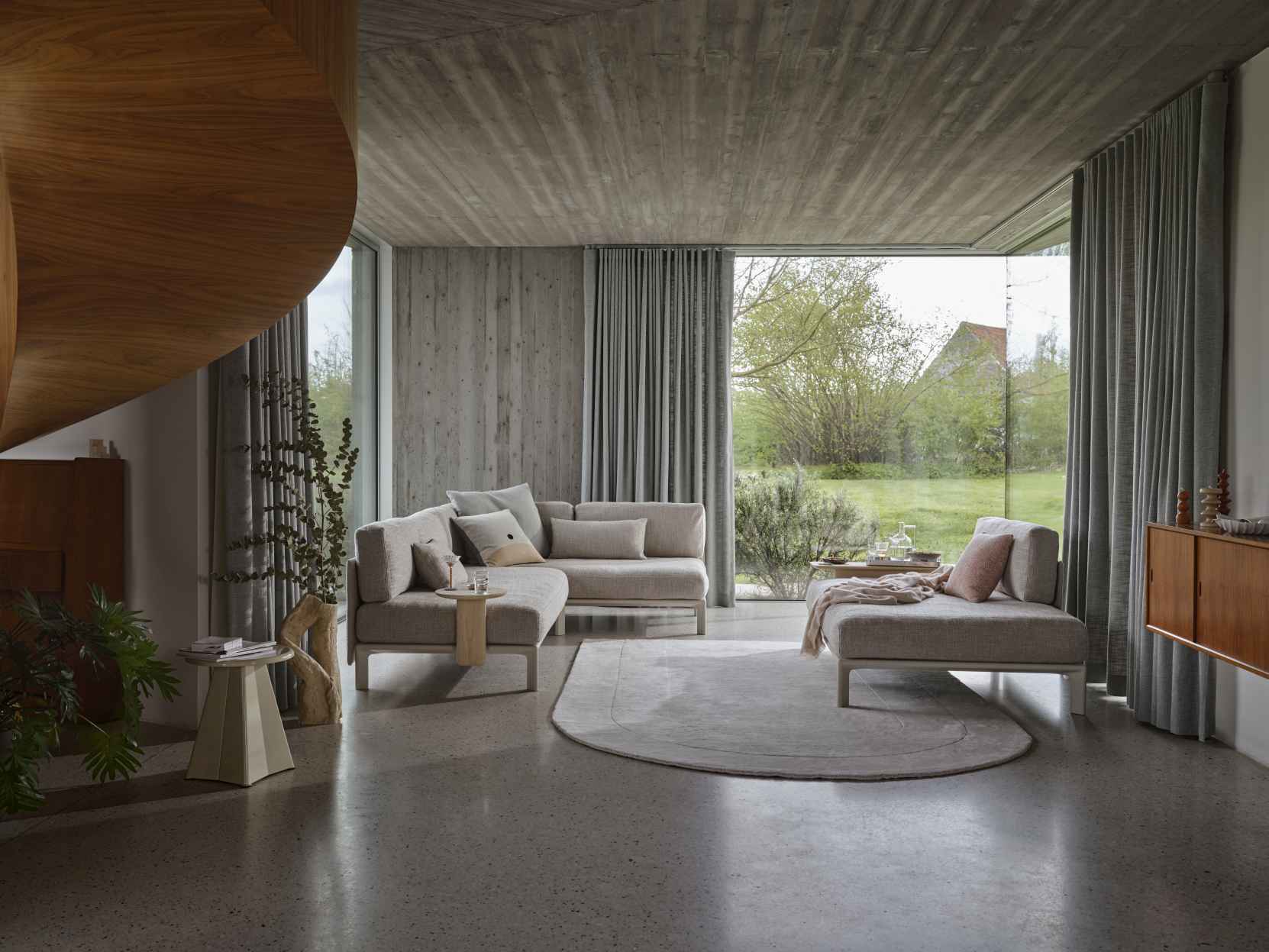 Helle Wohnzimmer-Szene mit modularem Vitra Anagram Sofa und passendem Sessel auf einem runden Teppich.