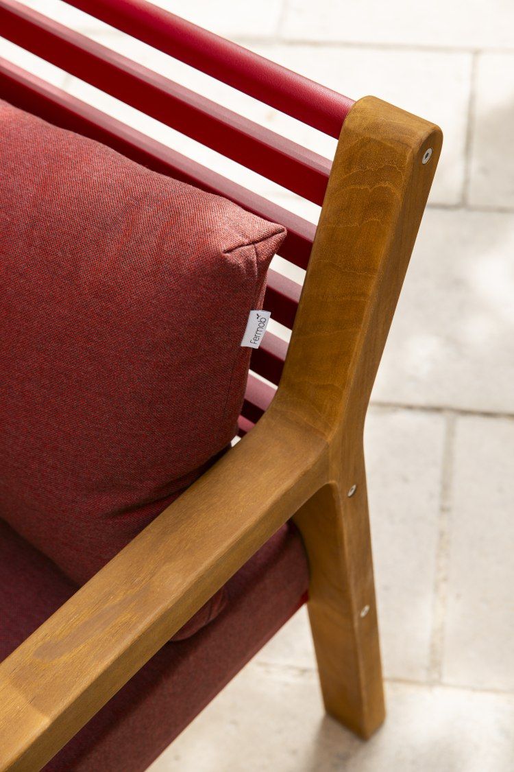 Detailaufnahme des Somerset Sessel Outdoor von Fermob mit rotem Kissen und Holzarmlehne.
