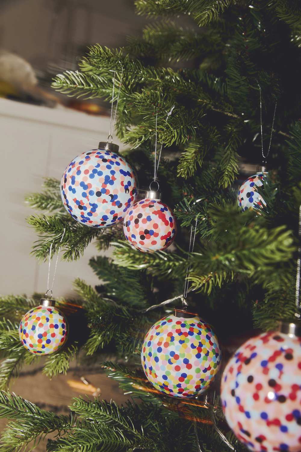 Mehrere Proust Weihnachtskugeln von Alessi mit bunten Punkten am Weihnachtsbaum.