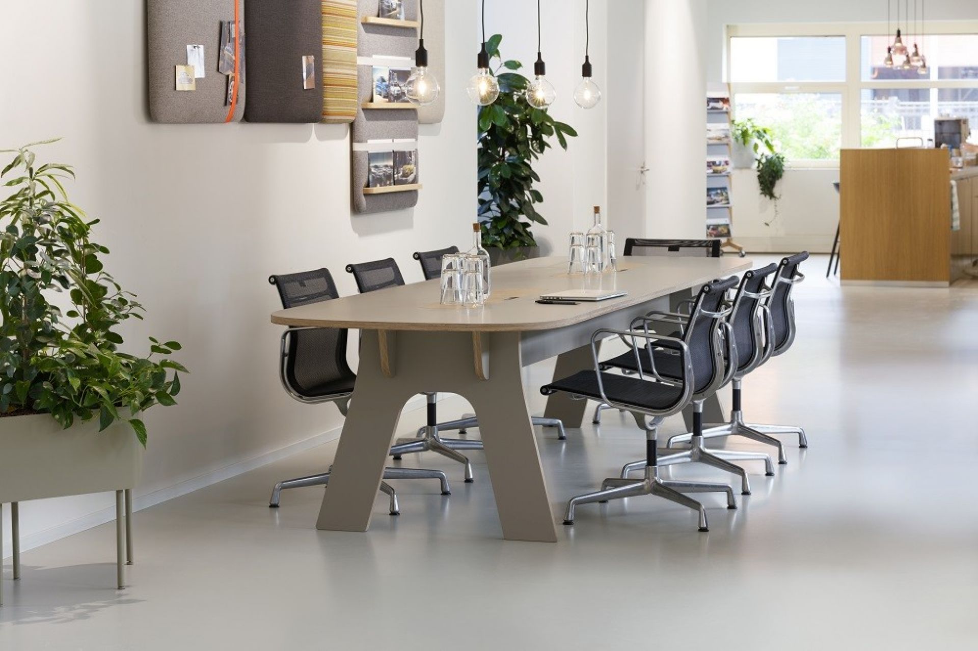 Büroraum mit langem Tisch, Stühlen und Cascando Pillow Wall Wandpaneelen für Notizen und Organisation.