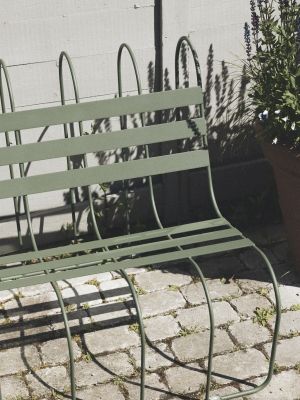 Nahaufnahme der grünen Gardener's Sofa Gartenbank von Design House Stockholm auf Pflastersteinen im Außenbereich.