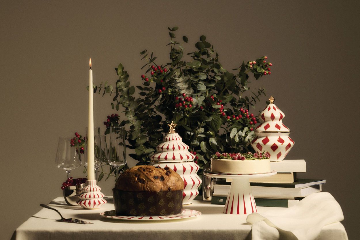 Festlicher Tisch mit Alessi Delight Kerzenständer, Panettone, Kuchen, Weihnachtsdeko und Eukalyptus für Weihnachten.