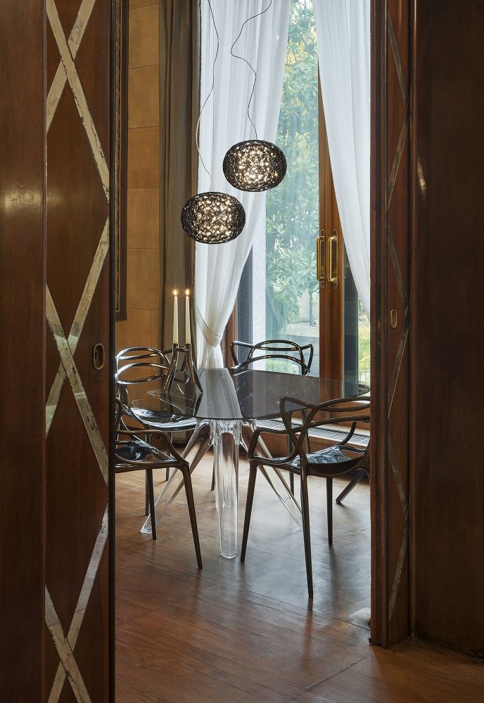 Zwei rauchfarbene Planet Pendelleuchten von Kartell hängen über einem Esstisch in einem eleganten Raum.