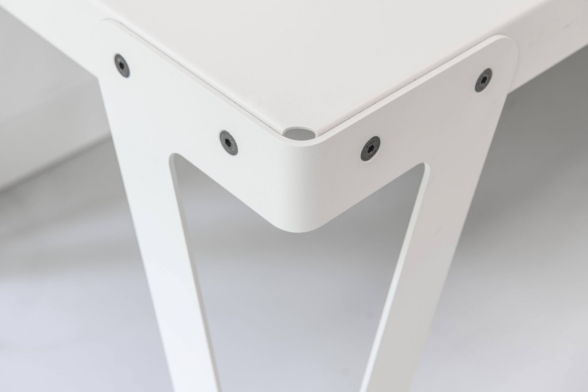 Detailaufnahme des weißen Lloyd Indoor Table Tisches mit Fokus auf Beinbefestigung und minimalistisches Design.