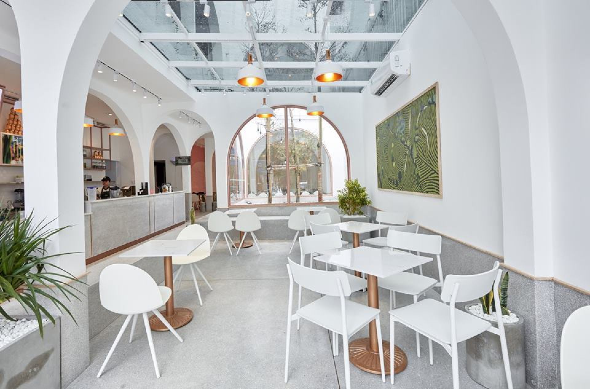 Innenansicht eines Cafés mit weißen Camel Stühlen von Segis und Tischen mit Marmorplatten.