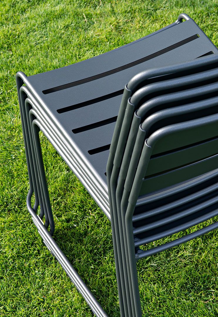 Stapel grauer Surprising Chair Stühle von Fermob für den Outdoor-Bereich auf Rasen.