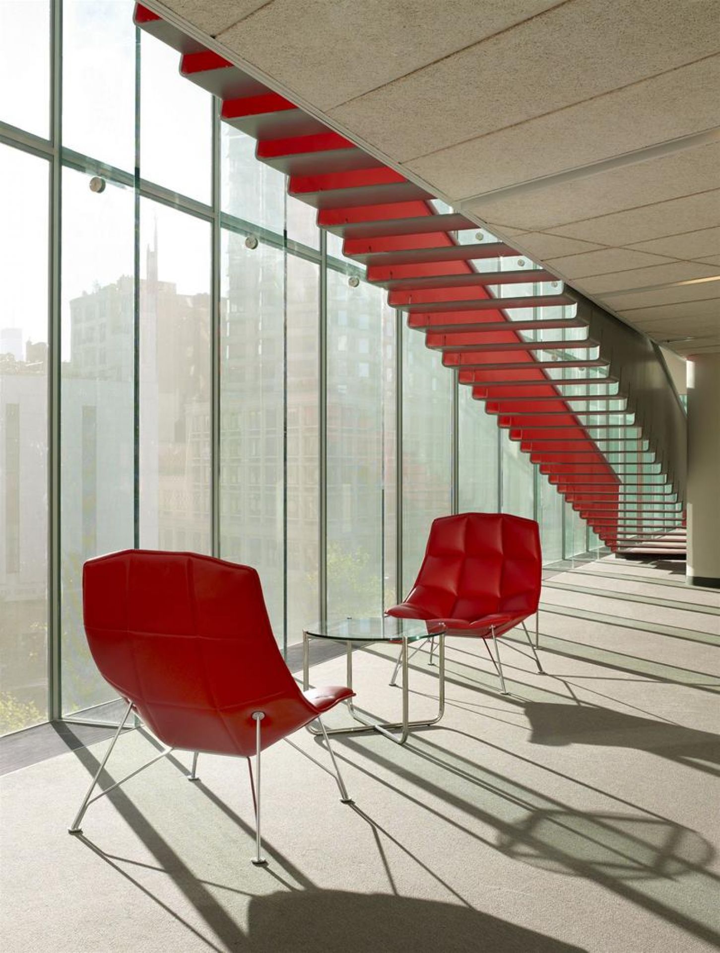 MR Couchtisch von Knoll International: Glascouchtisch mit zwei roten Sesseln in modernem Büro.