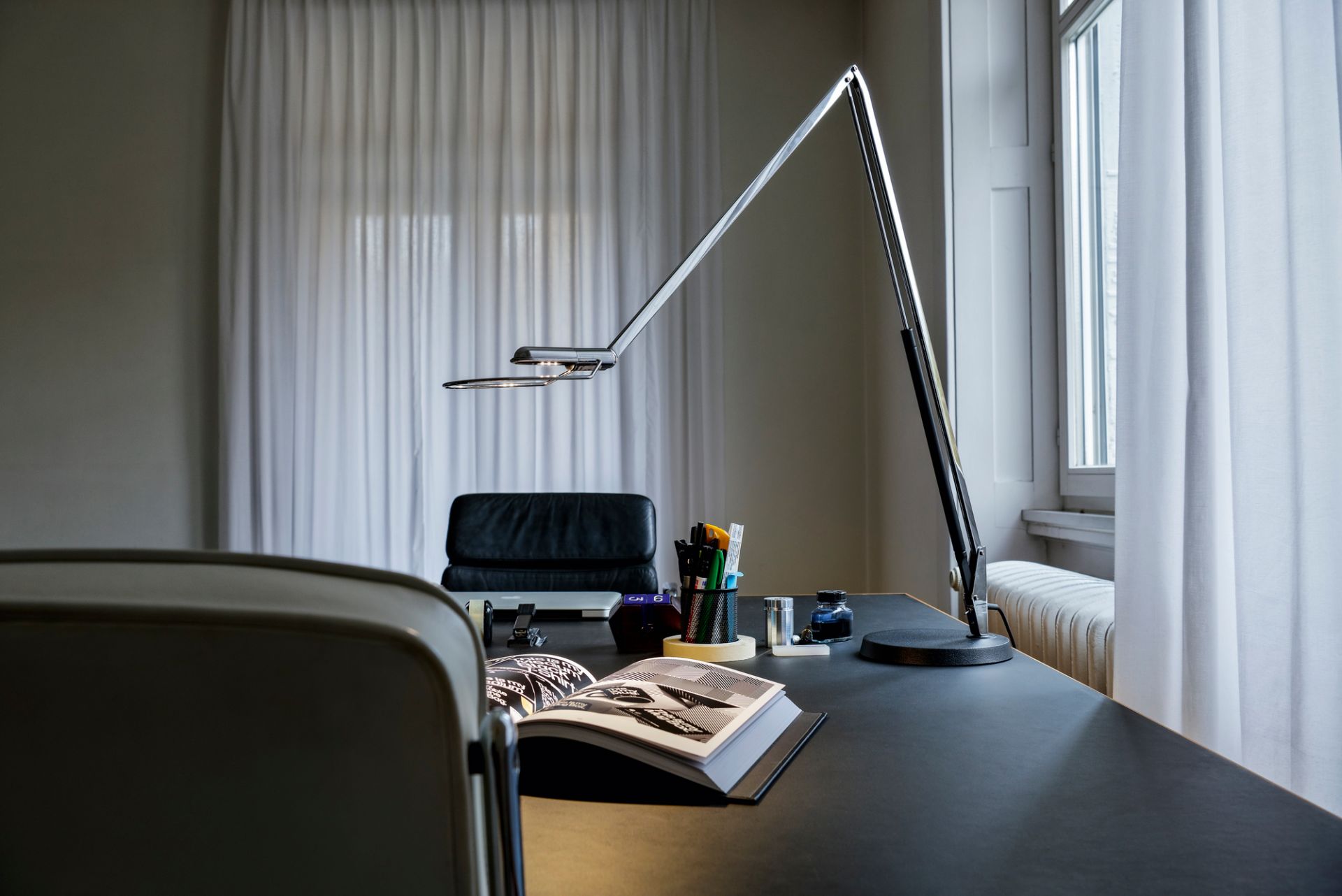 Liftolino LED Tischleuchte von Belux auf einem Schreibtisch, dimmbare Arbeitsplatzleuchte aus Aluminium.