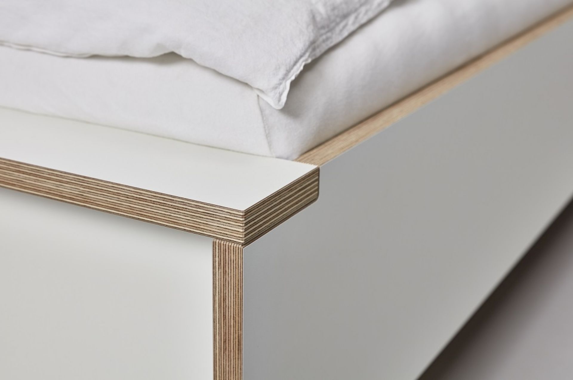 Detailaufnahme vom Flai Einzelbett von Müller Möbelwerkstätten, weißes Bett mit hellem Holzrahmen.
