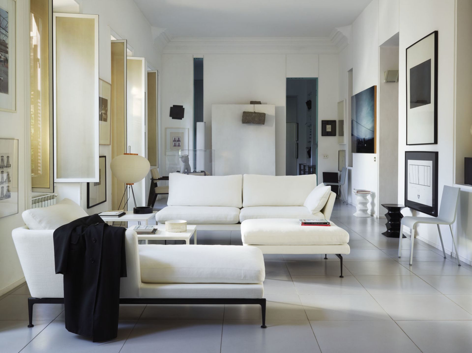 Heller Wohnraum mit Vitra .03 Stuhl, weißen Sofas und moderner Kunst. Designermöbel für stilvolles Wohnen.