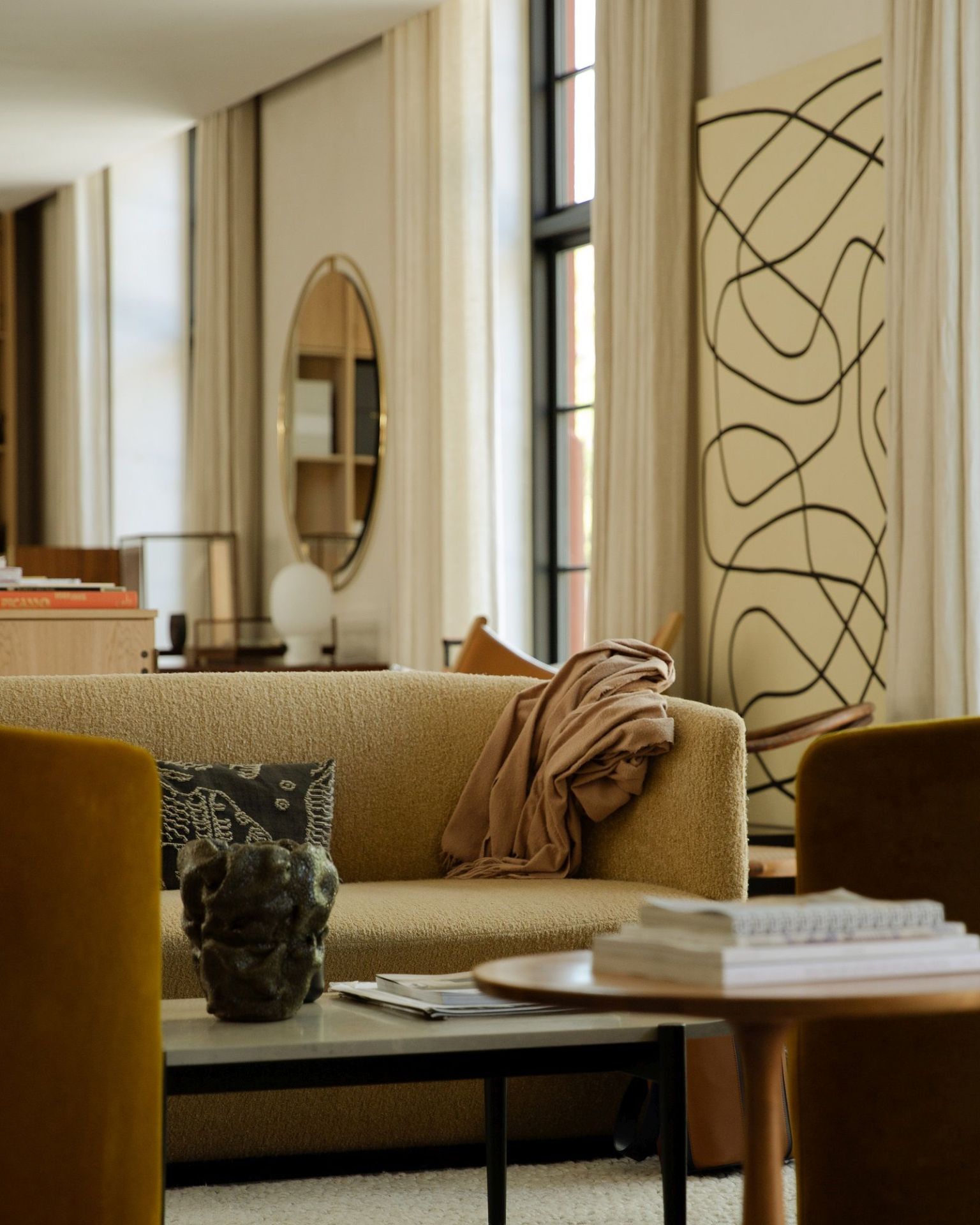 Ansicht eines Wohnzimmers mit Audo Copenhagen Nimbus Mirror, Sofa, Couchtisch und Kunstobjekten.