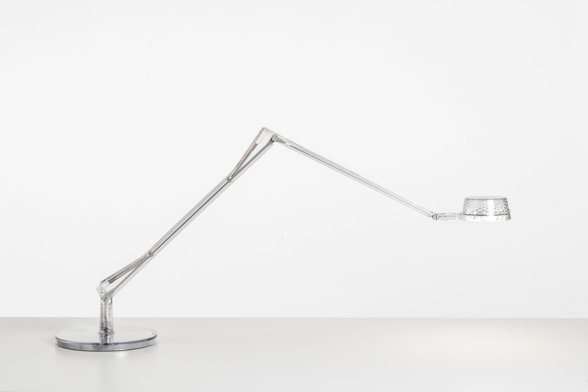Aledin Tischleuchte von Kartell, moderne LED Schreibtischlampe mit transparentem Gestell und rundem Fuß.