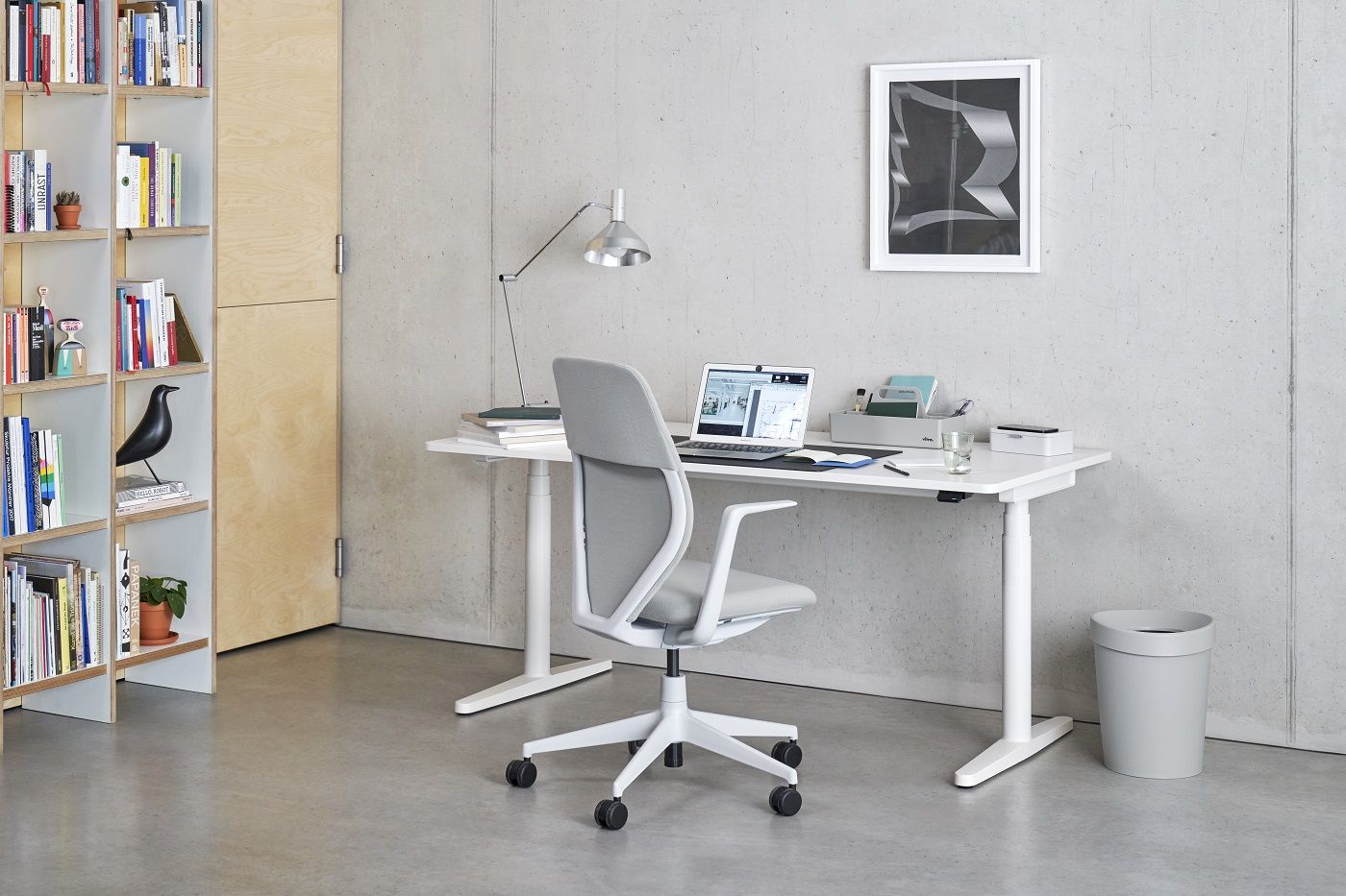 Grauer ACX Soft Bürodrehstuhl von Vitra vor einem Schreibtisch in einem modernen Büro.