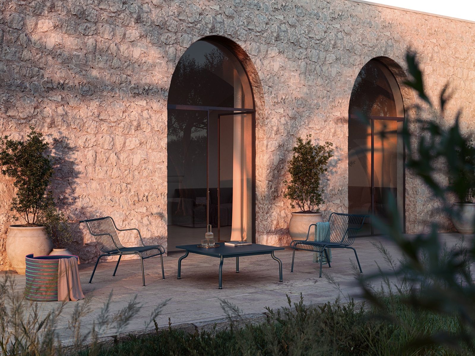 South Outdoor Lounge Armchair Sessel von Magis auf einer Terrasse mit Steinfliesen und Pflanzen.