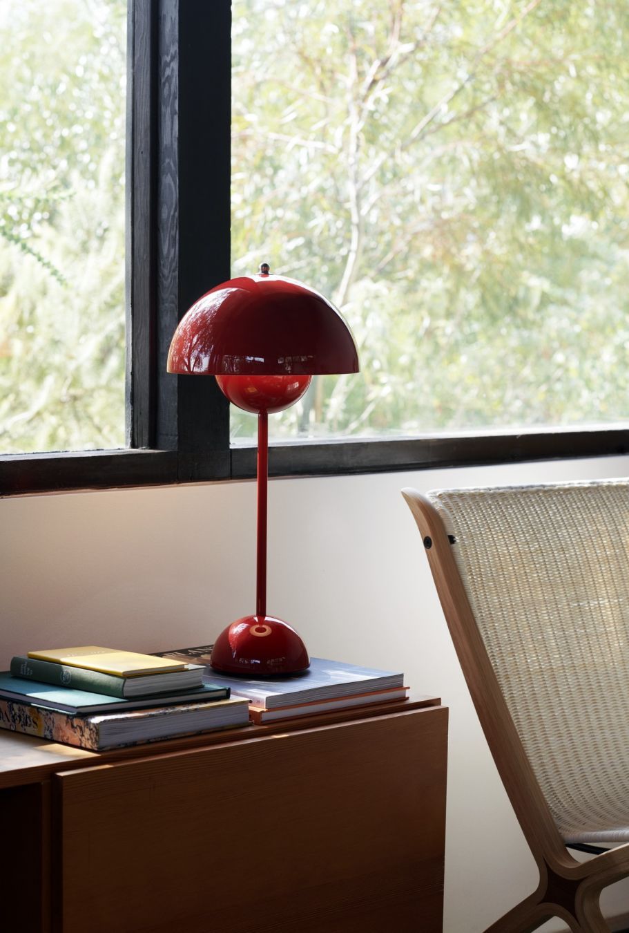 Rote Flowerpot VP3 Tischleuchte von AndTradition auf einem Nachttisch mit Büchern, neben einem Fenster.