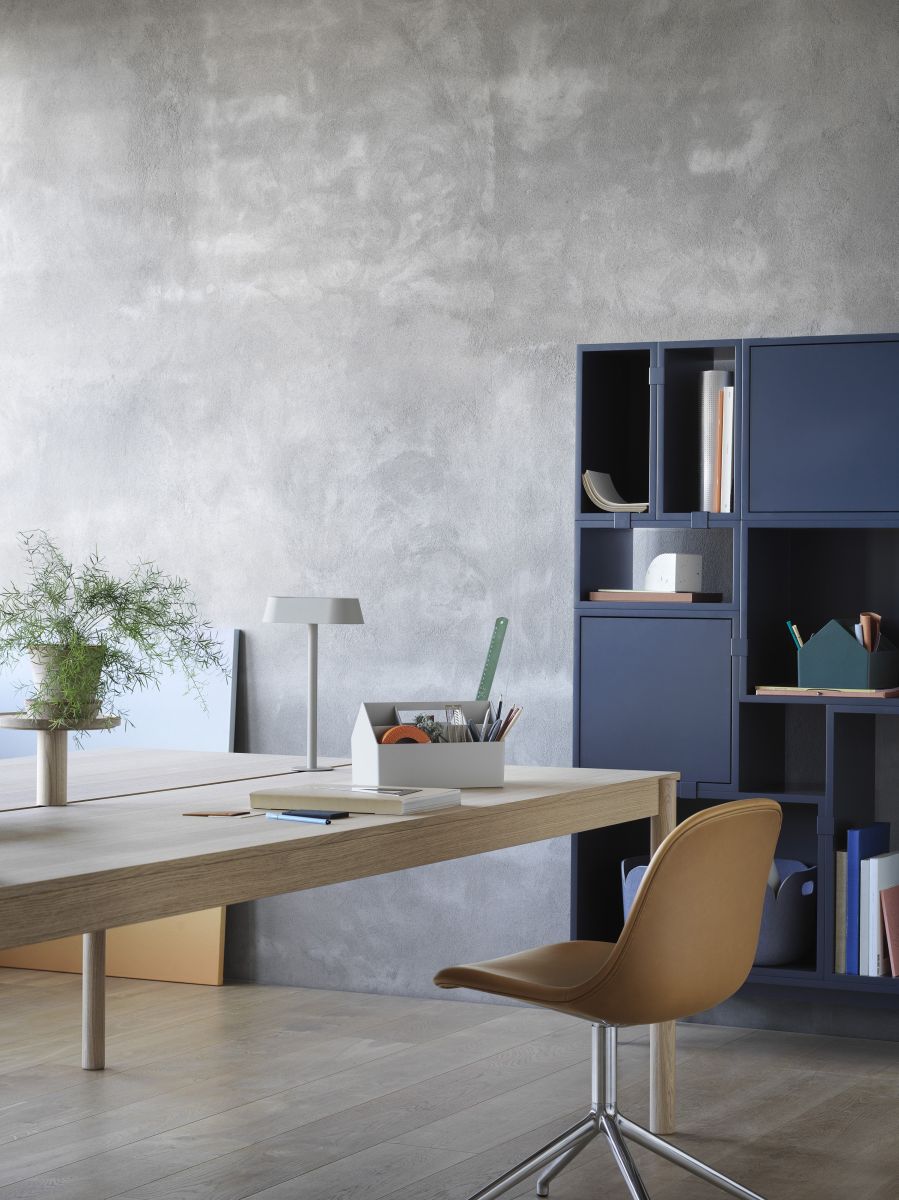 Muuto Sketch Toolbox, eine weiße Organisationsbox mit Büromaterialien auf einem Schreibtisch. Im Hintergrund ein blaues Regal.