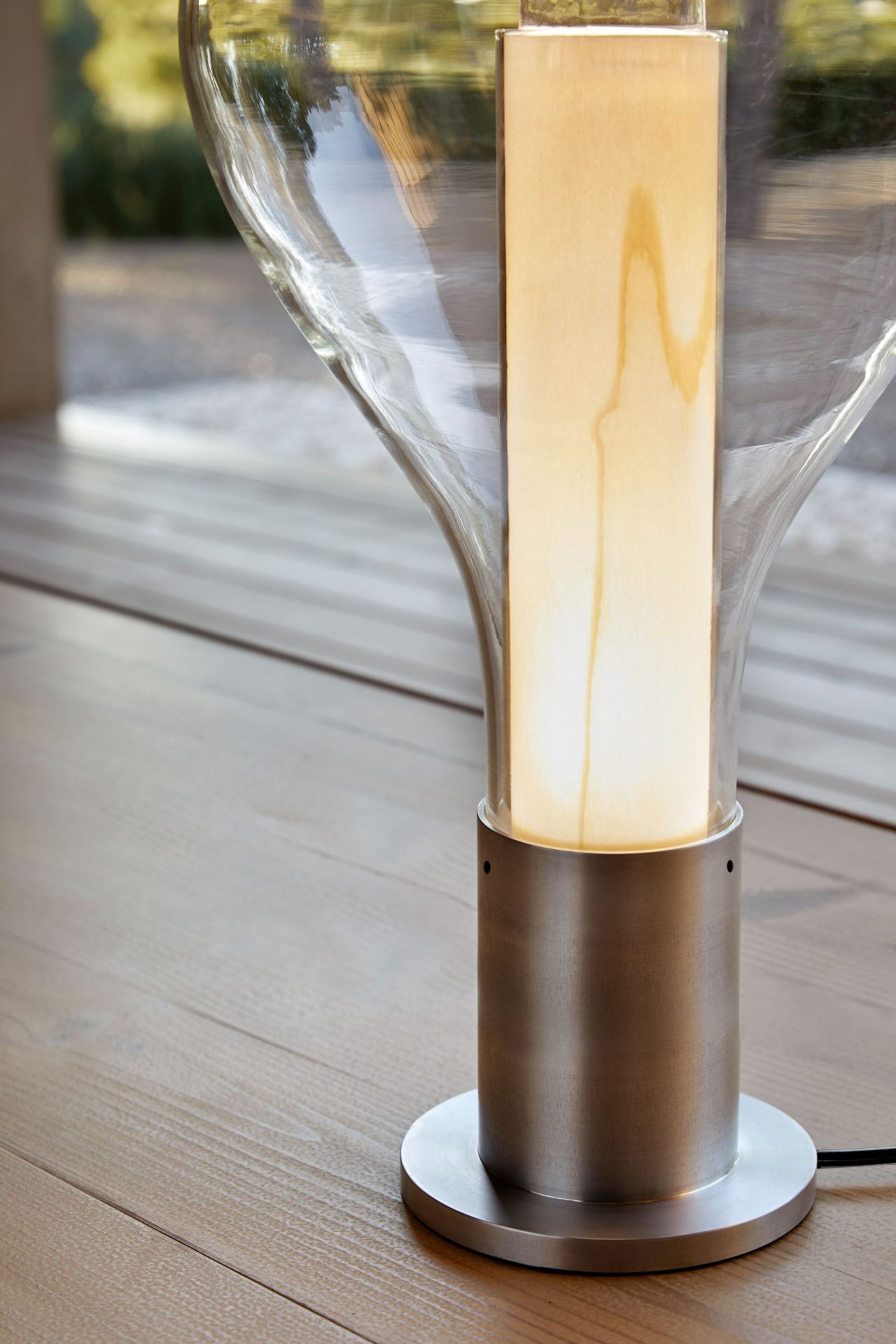Eris Tischleuchte von LZF Lamps mit Aluminiumsockel und hellrosa Lampenschirm auf Holzboden.