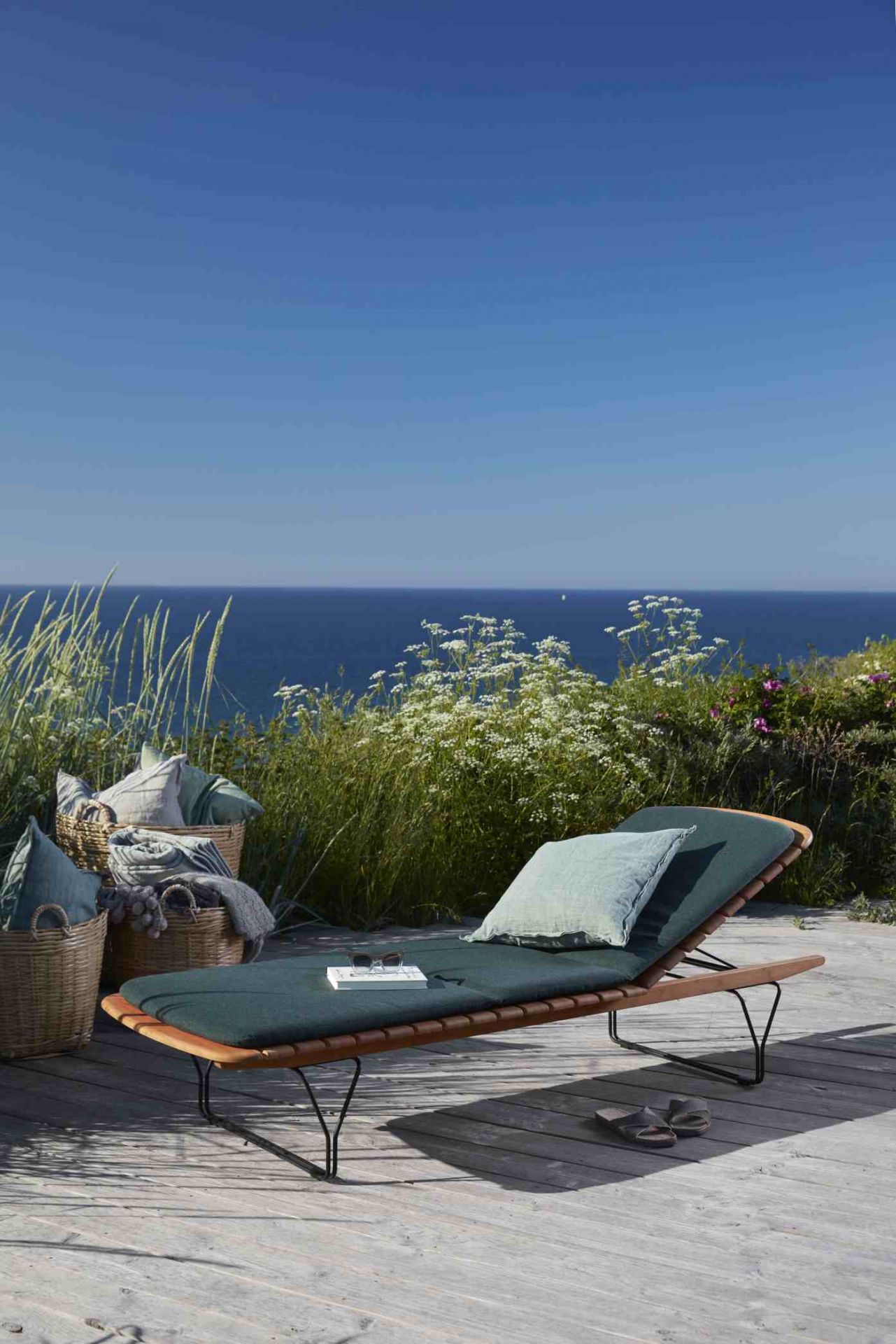 Houe Sonnenliege mit Molo Outdoor Kissen in Grün vor Meer und Dünenlandschaft für entspannte Stunden.