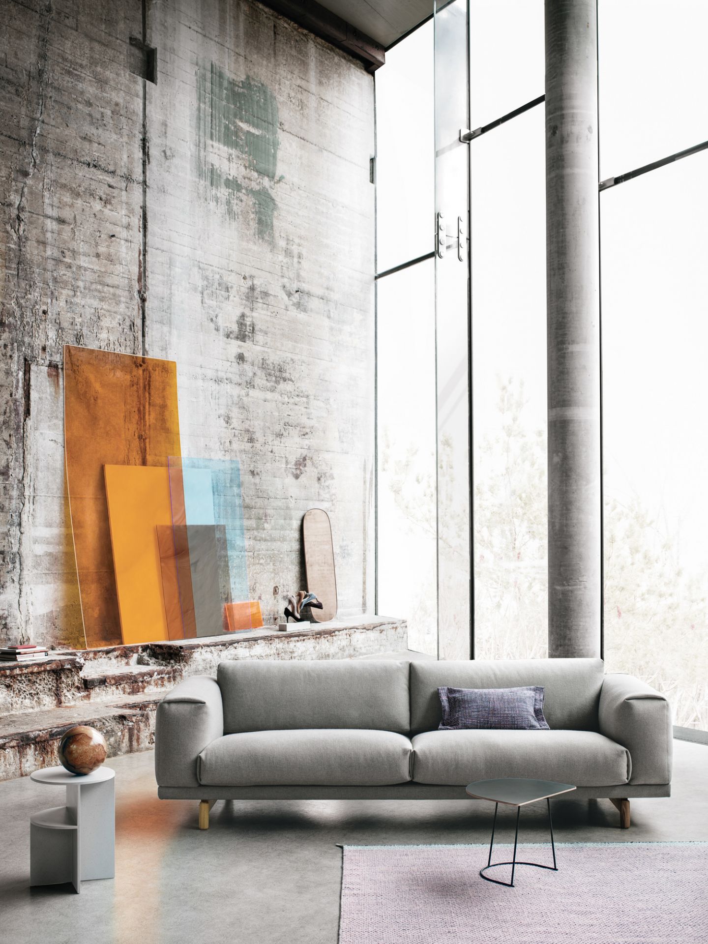 Heller Wohnraum mit grauem Sofa, Muuto Airy Coffee Table Beistelltisch und kleinem, dunklen Couchtisch auf einem Teppich.