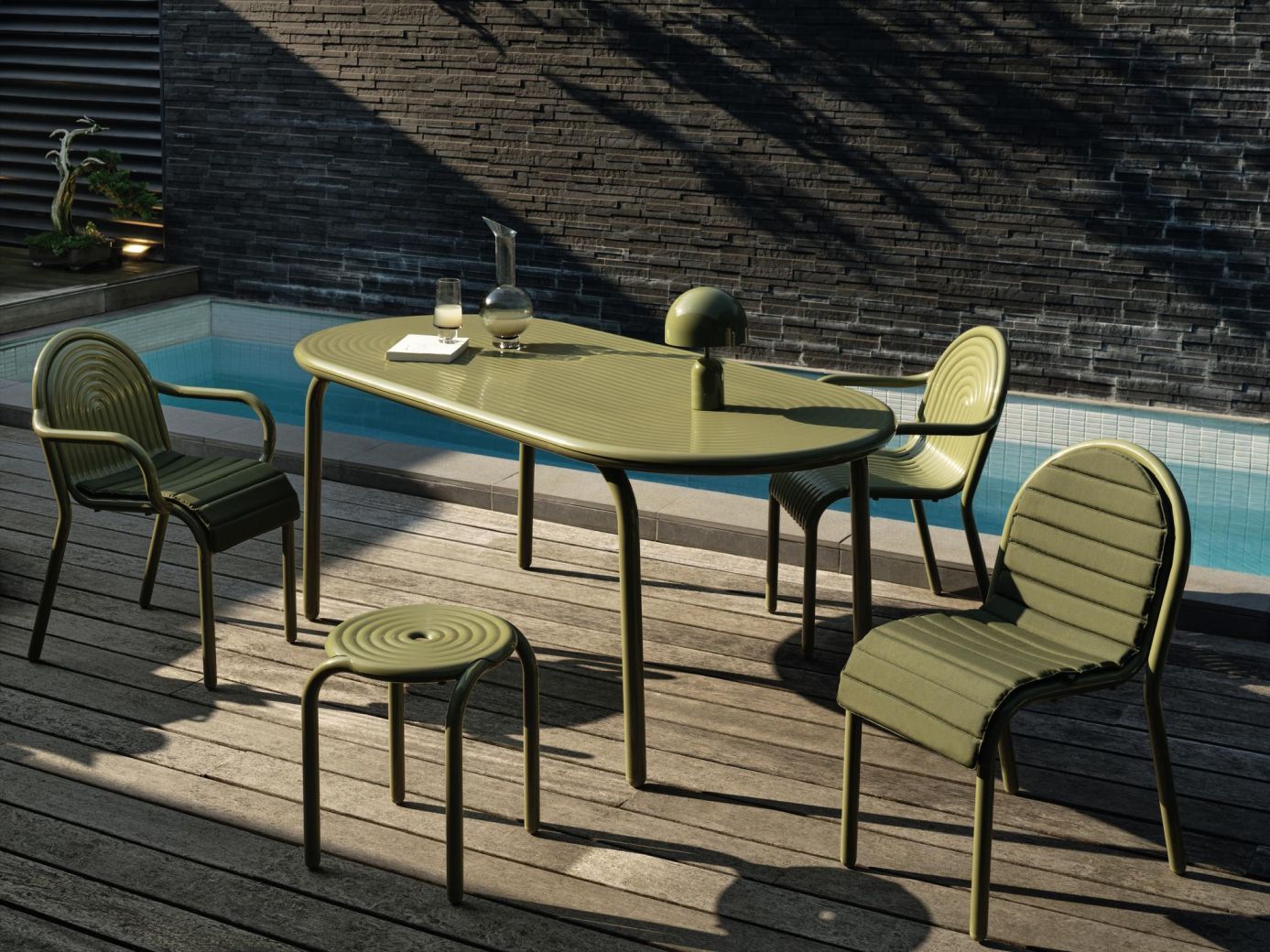 Groove Outdoor Tisch von Tom Dixon in Putty mit Stühlen und Hocker auf Holzterrasse.