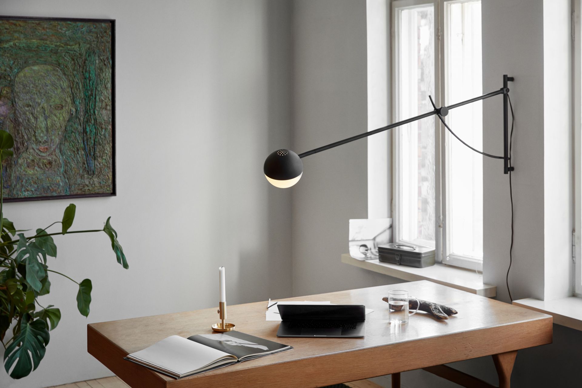 Schwarze Balancer Wandleuchte von Northern über einem Schreibtisch mit Laptop, Buch und Dekoration im modernen Arbeitszimmer.