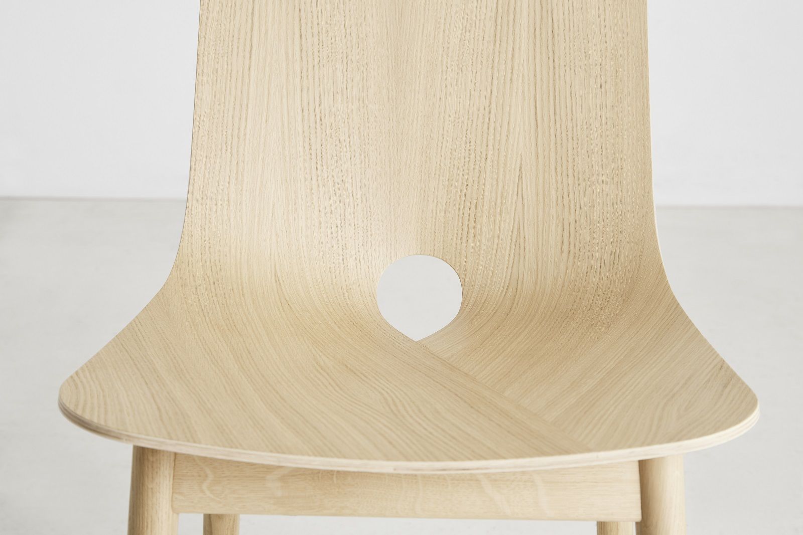Nahaufnahme des hellen Holzstuhls Mono Dining Chair von Woud mit charakteristischer Lochung.