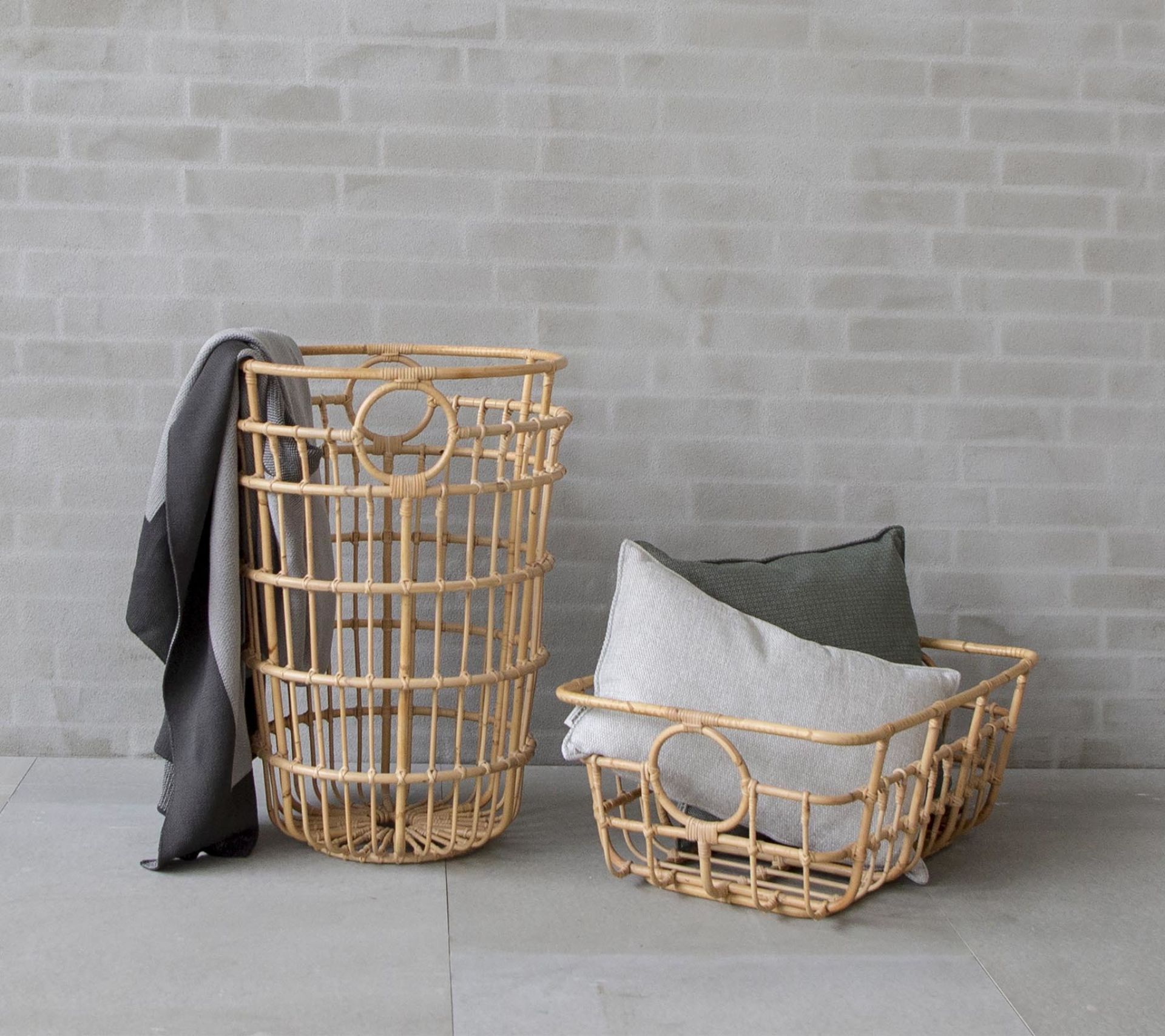 Zwei Cane-Line Körbe, ein hoher und ein flacher, aus Rattan mit Kissen und Decke.