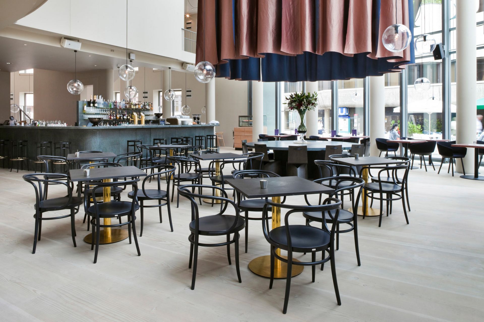 Innenansicht eines Restaurants mit vielen schwarzen 209 Bugholz Thonet Stühlen und Tischen.