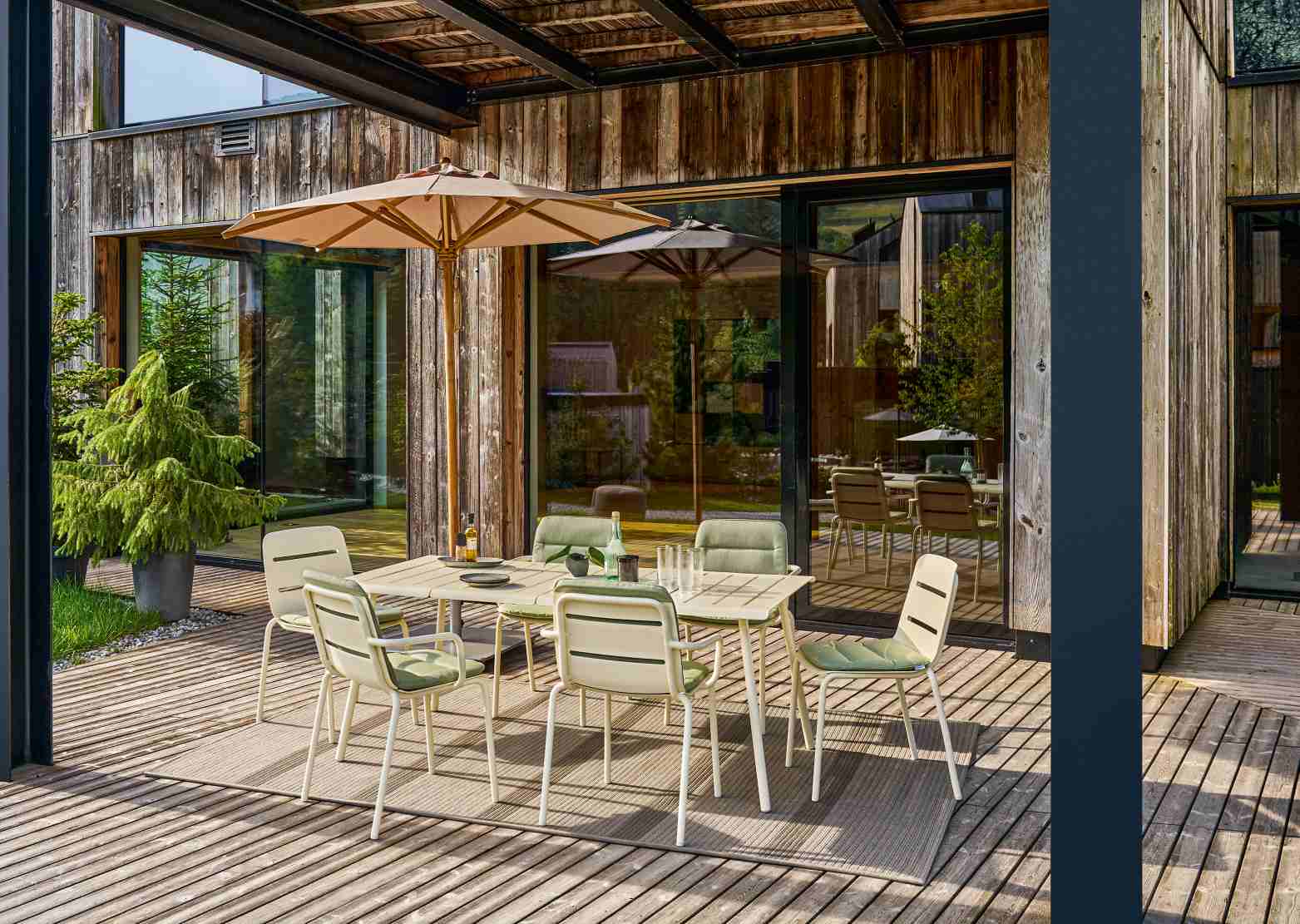 Weishäupl Vapio Sessel Outdoor auf Holzterrasse mit Esstisch und Sonnenschirm, Gartenmöbel für den Außenbereich.