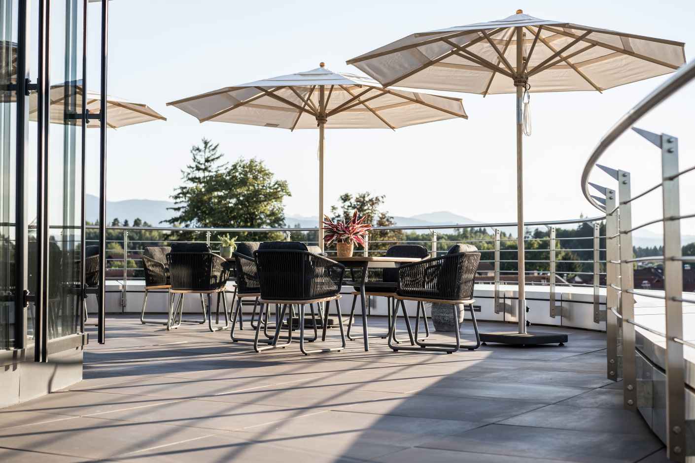 Weishäupl Klassiker Sonnenschirme und Gartenmöbel auf einer Terrasse mit Bergblick, ideal für entspannte Stunden im Freien.