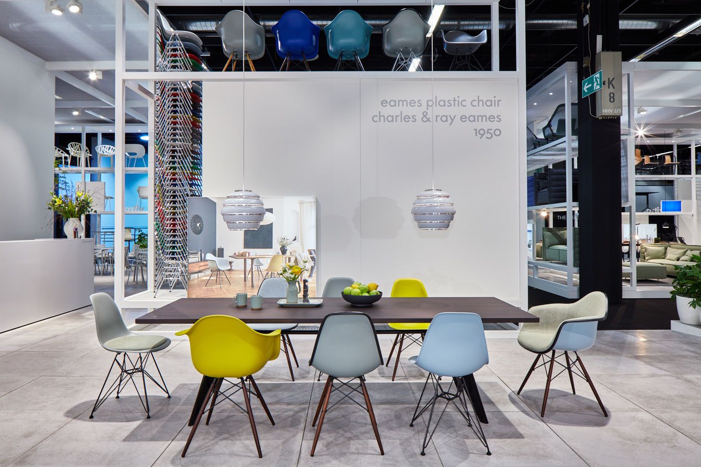 Esstisch mit mehreren bunten Eames DSW Stühlen mit Sitzpolster von Vitra im Möbelhaus.