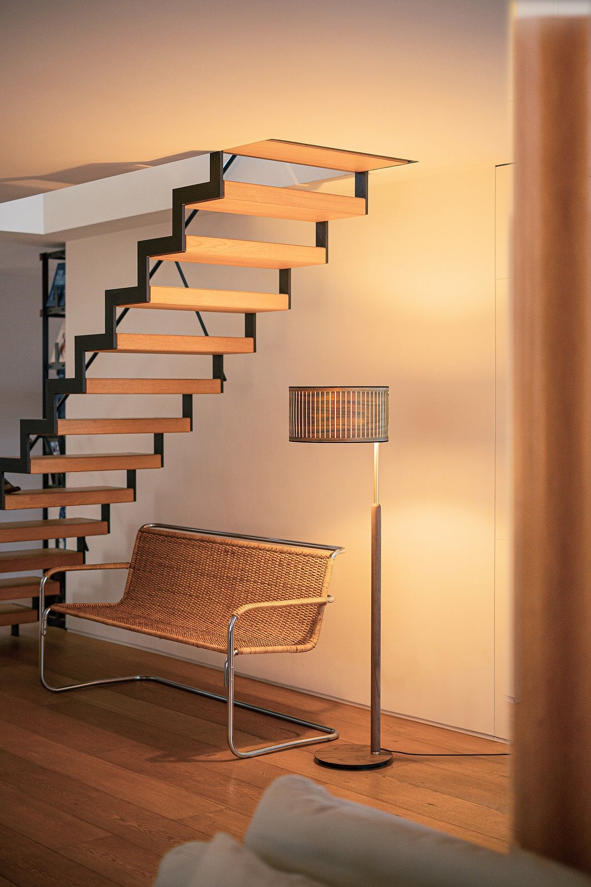 Autumn Floor Lamp Stehleuchte von Nomon neben Rattansessel und Treppe in modernem Wohnzimmer.