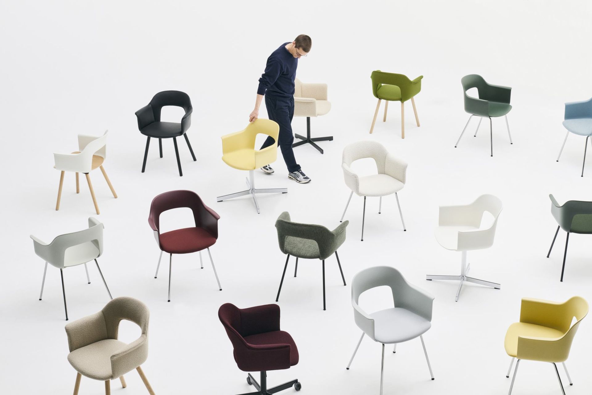 Layout Armchair 213 von Hay: Mann arrangiert farbenfrohe Armlehnstühle auf weißem Hintergrund für E-Commerce-Produktkatalog.
