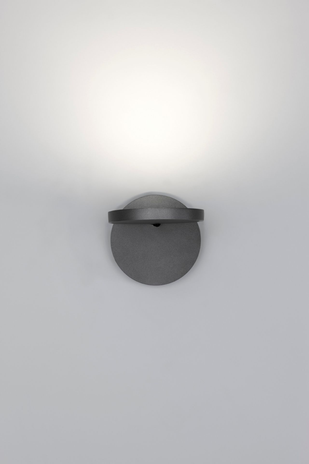 Nahaufnahme der grauen Demetra Wandleuchte von Artemide mit Schalter und warmem Lichtschein.