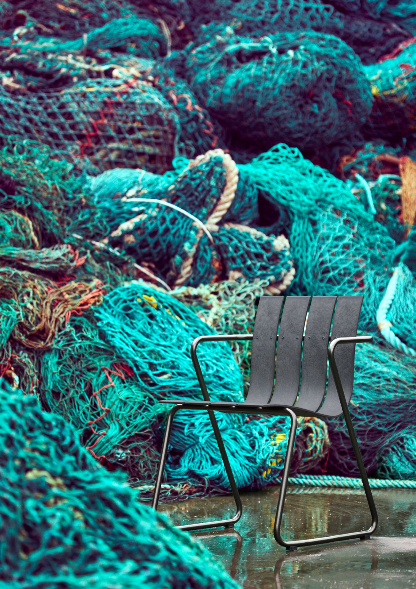 Schwarzer Ocean Chair Outdoor Stuhl von Mater vor einem Hintergrund aus Fischernetzen. Nachhaltige Gartenmöbel.