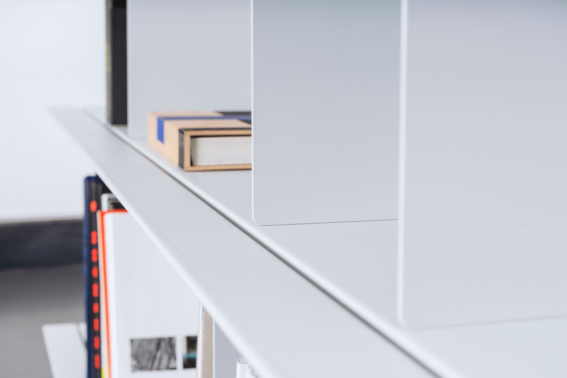 Detailaufnahme eines weißen Zoll D Regals von Nils Holger Moormann mit Büchern und minimalistischem Design.