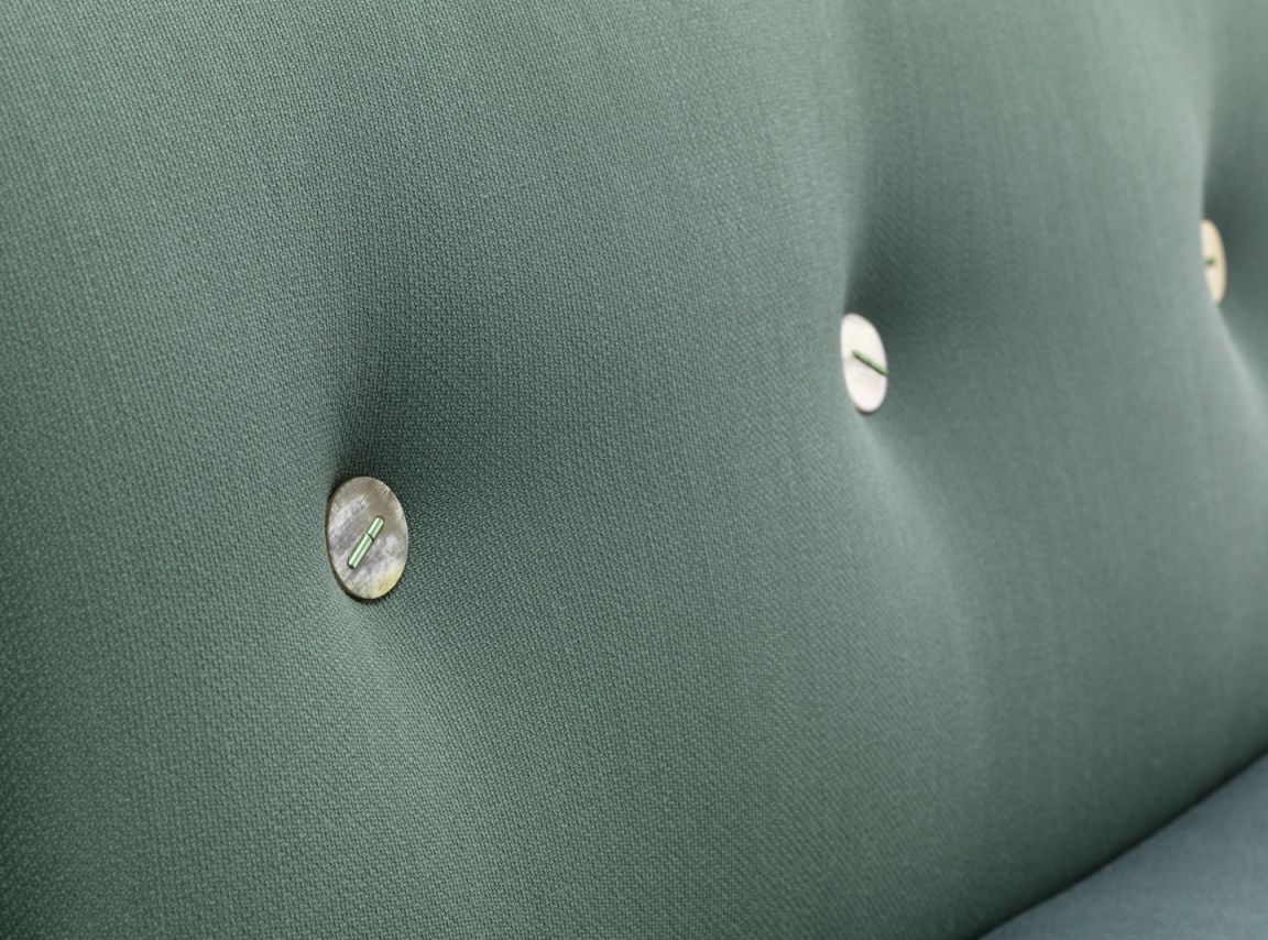 Detailaufnahme des grünen Vitra Polder Sofas mit Knopfheftung und auffälligen Knöpfen.