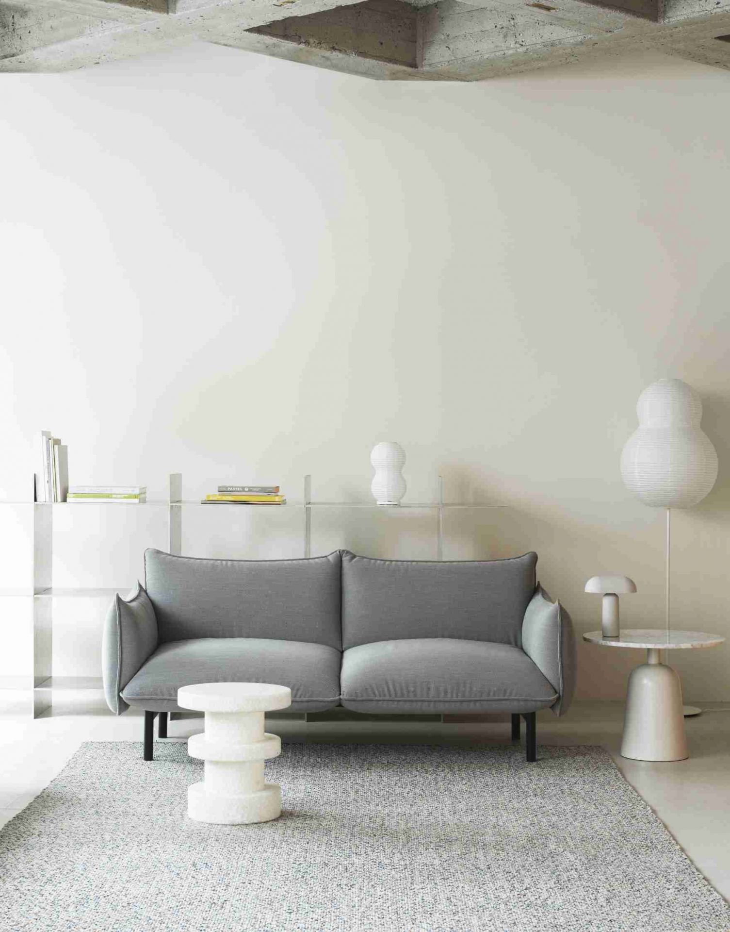 Weißer Bit Stool Stack Hocker von Normann Copenhagen vor grauem Sofa auf Teppich.