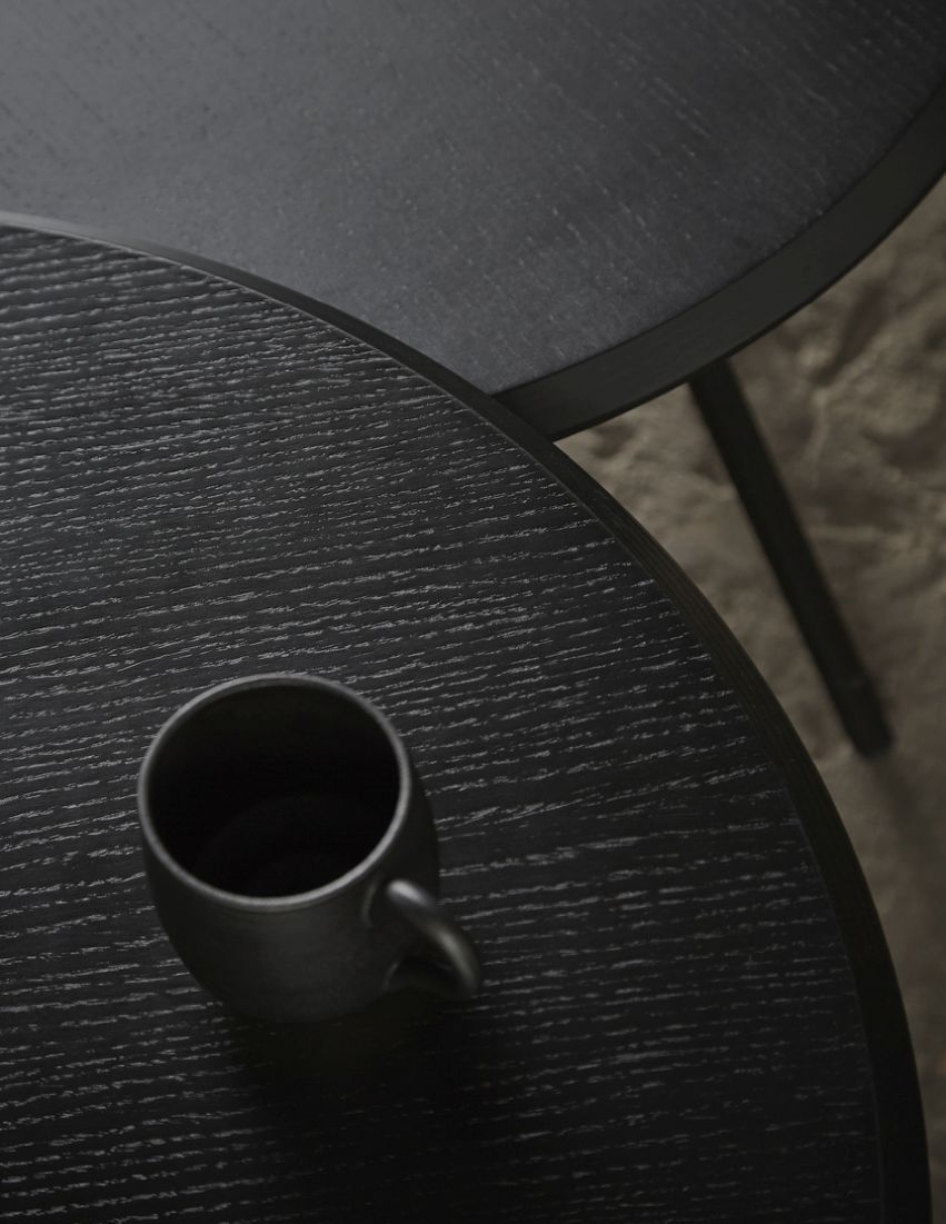 Nahaufnahme: Schwarzer Soround Beistelltisch aus Eiche mit Tasse, modernes Designmöbel für Wohnzimmer.